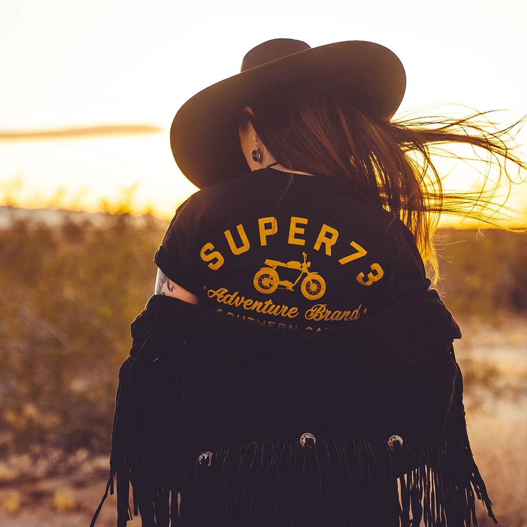 Back of female model wearing black super73 tshirt with wind in hair