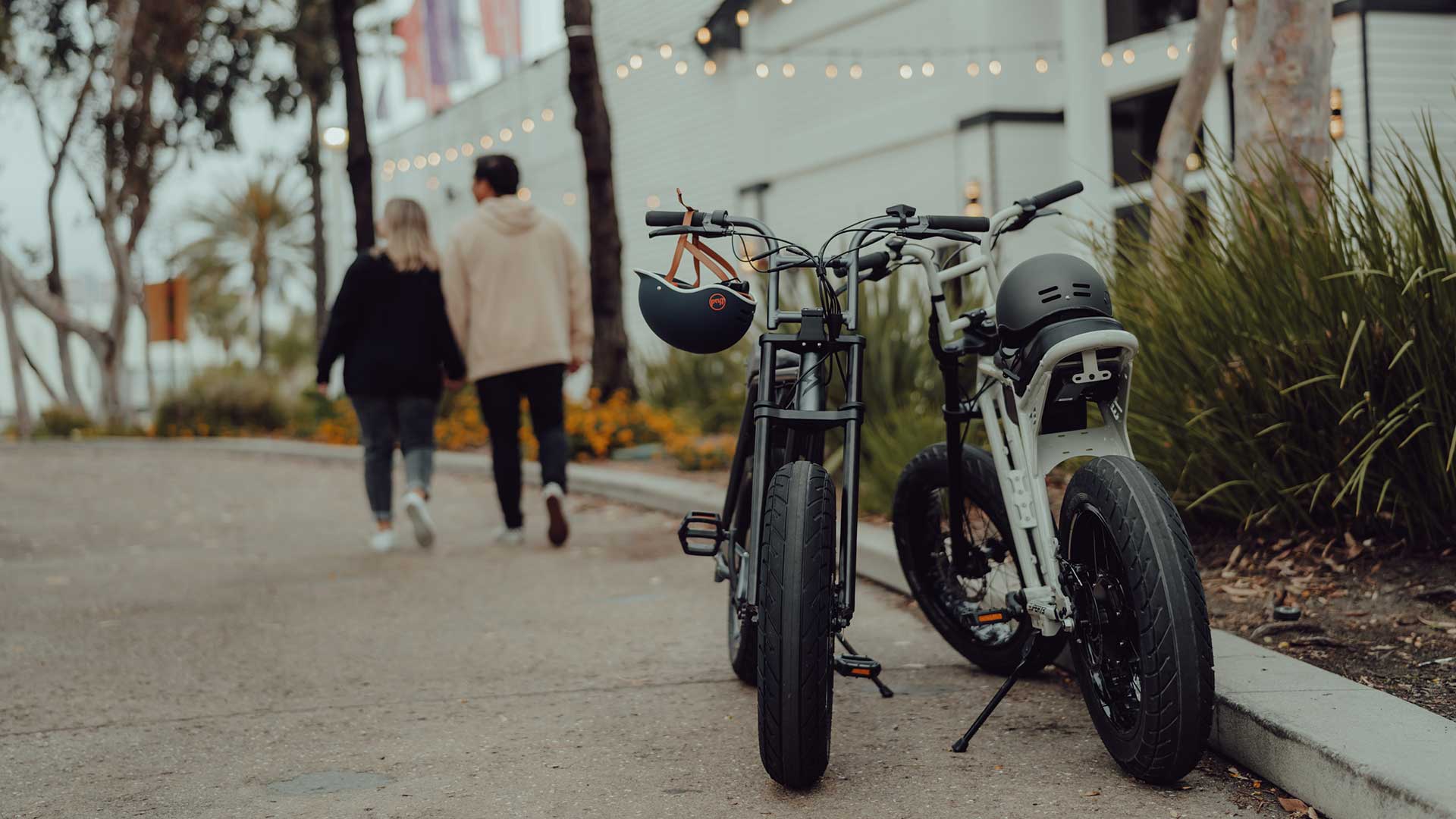 A pair of riders walking away from parked super73 bikes.