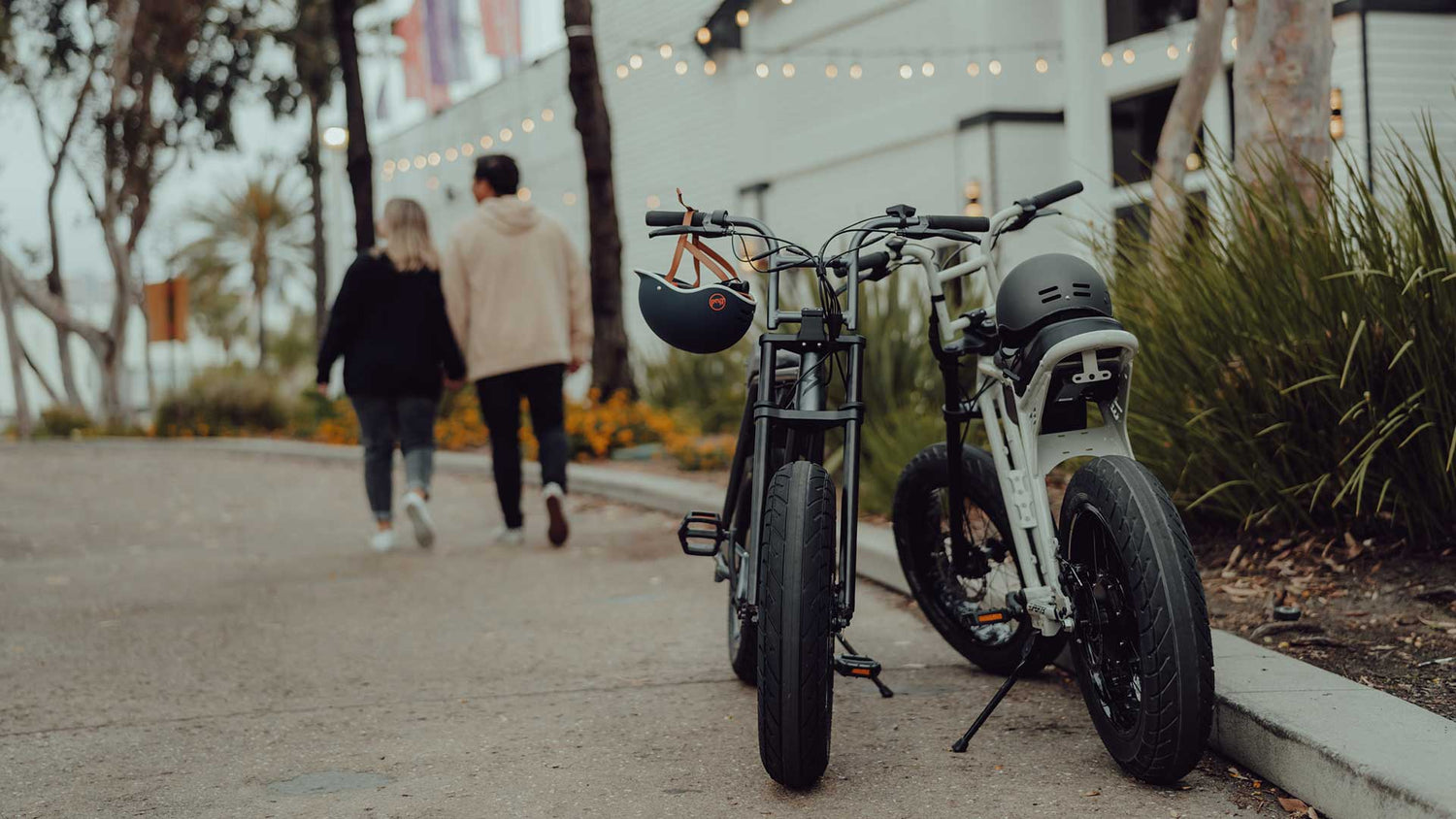 A pair of riders walking away from parked super73 bikes.