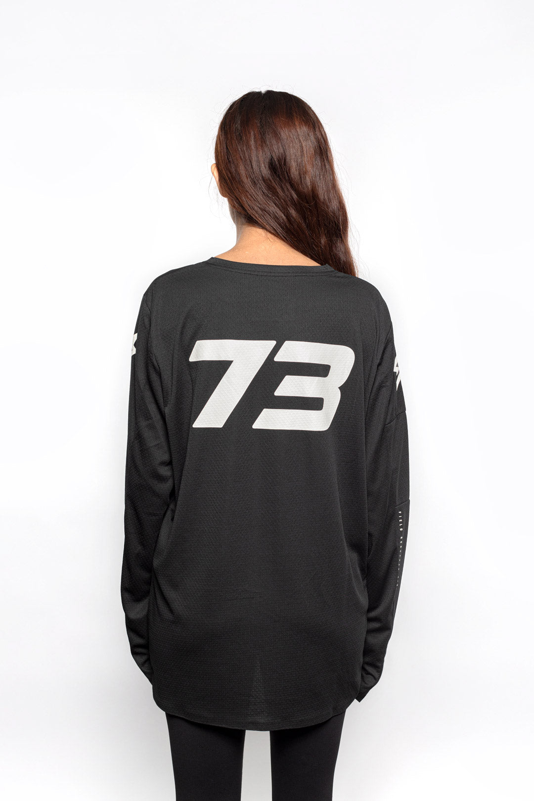 Female model back view of black Premium long sleeve athletic moto hoon jersey.