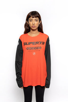 Female model front view of orange Premium long sleeve athletic moto hoon jersey.