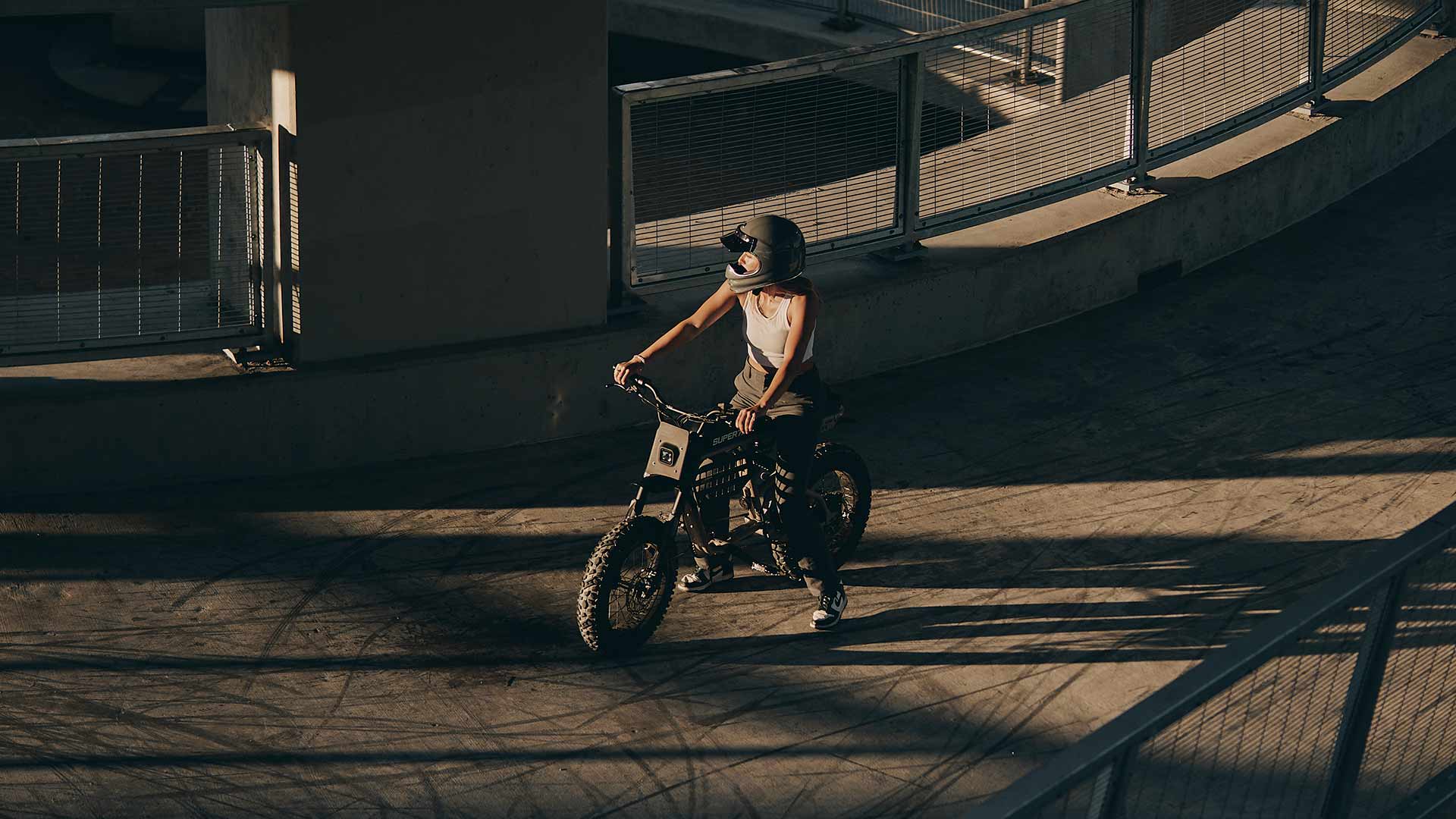 Rider in a tank top and helmet sitting on a Super73 ebike on an urban highway