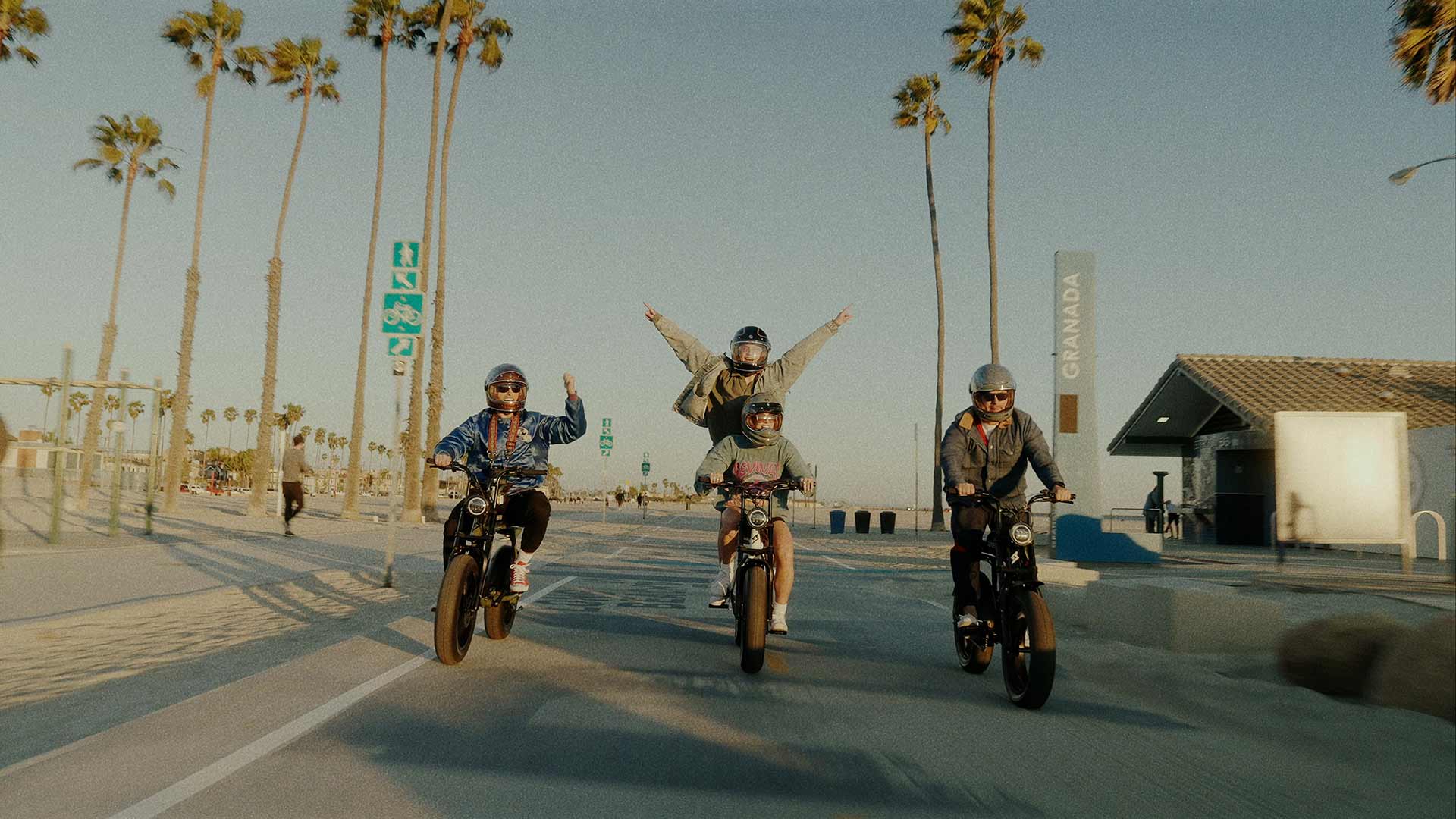 Friends riding their SUPER73 E-bikes along the beach boardwalk