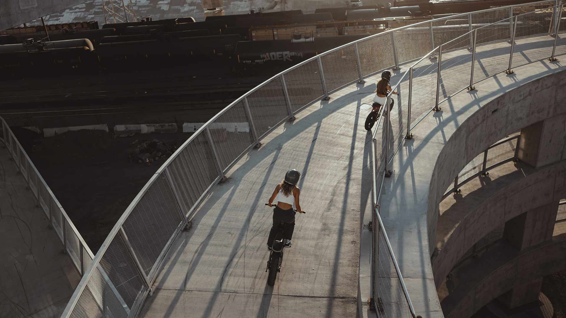 Riders descending rounded pedestrian overpass ramp on Super73 ebikes