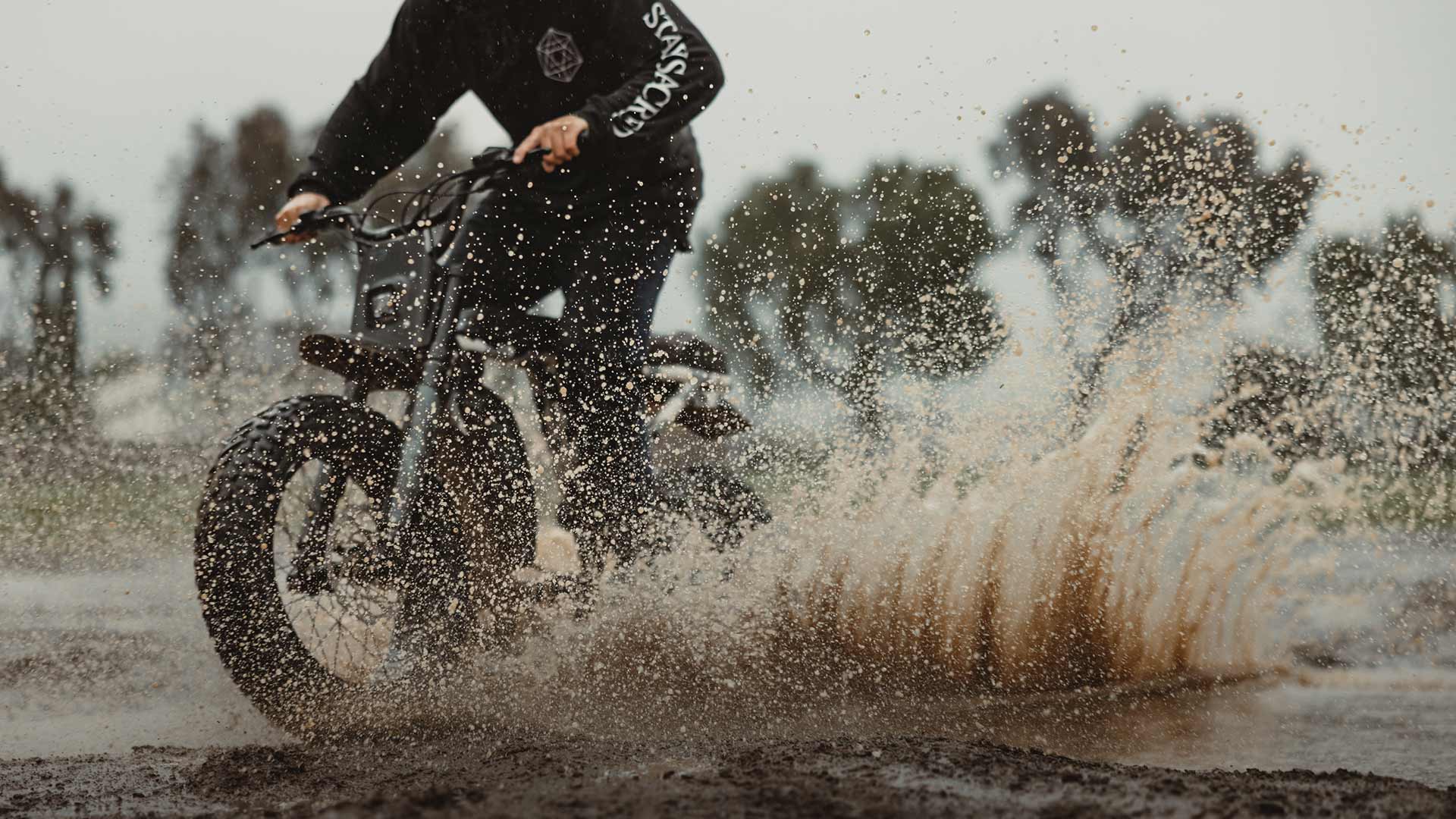 The Super73-R Adventure Series ebike riding through the mud and kicking up water