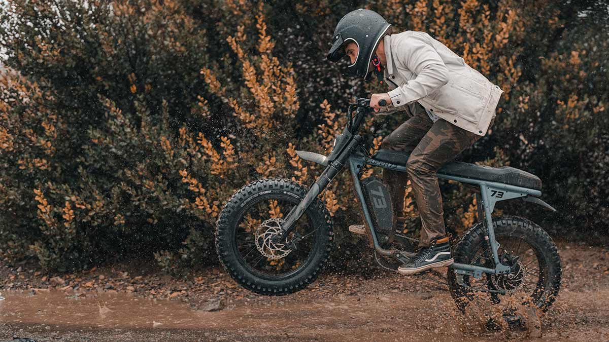 The Super73-S Adventure Series ebike riding through the mud doing a wheelie