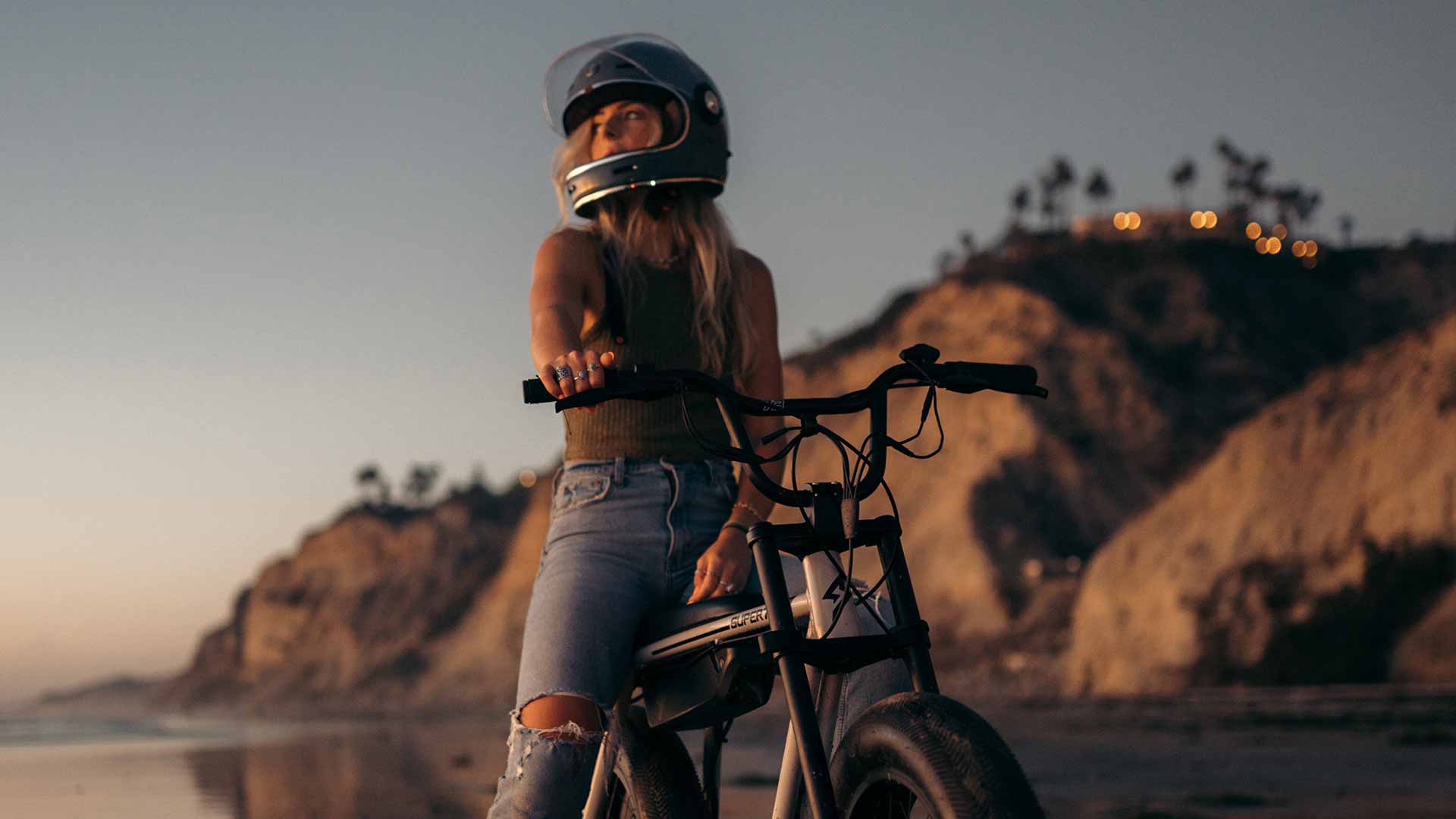 Young woman on a Super73 ebike at sunset with her hand on the handlebar throttle