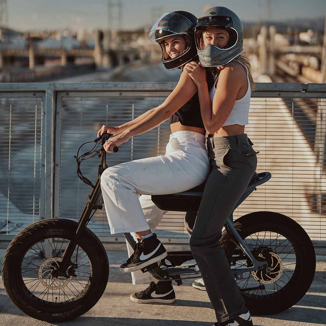 Two young girls sitting on their super73 zx panthro blue in front of the LA river