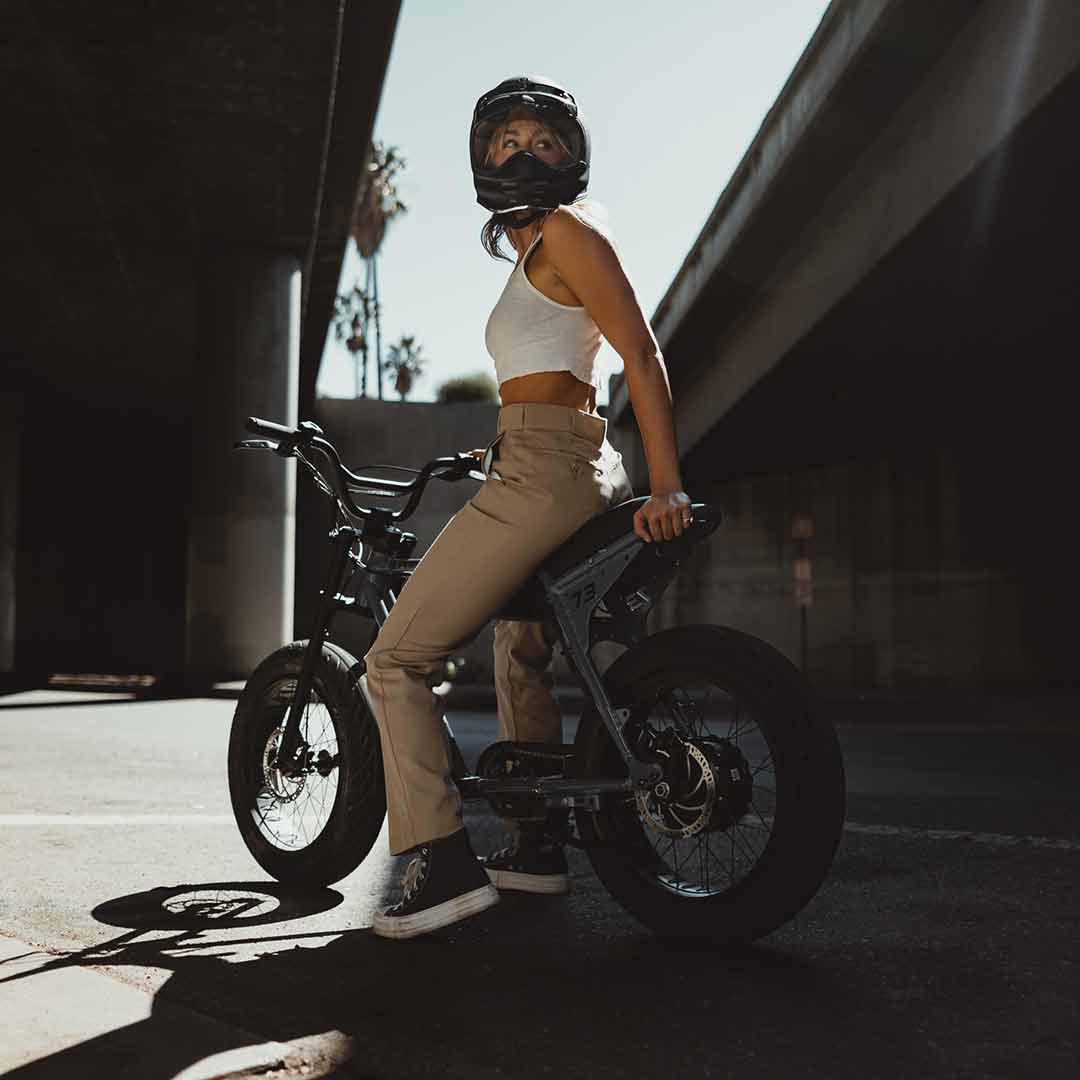 A woman sitting on her super73 panthro blue zx in the street looking back at the camera