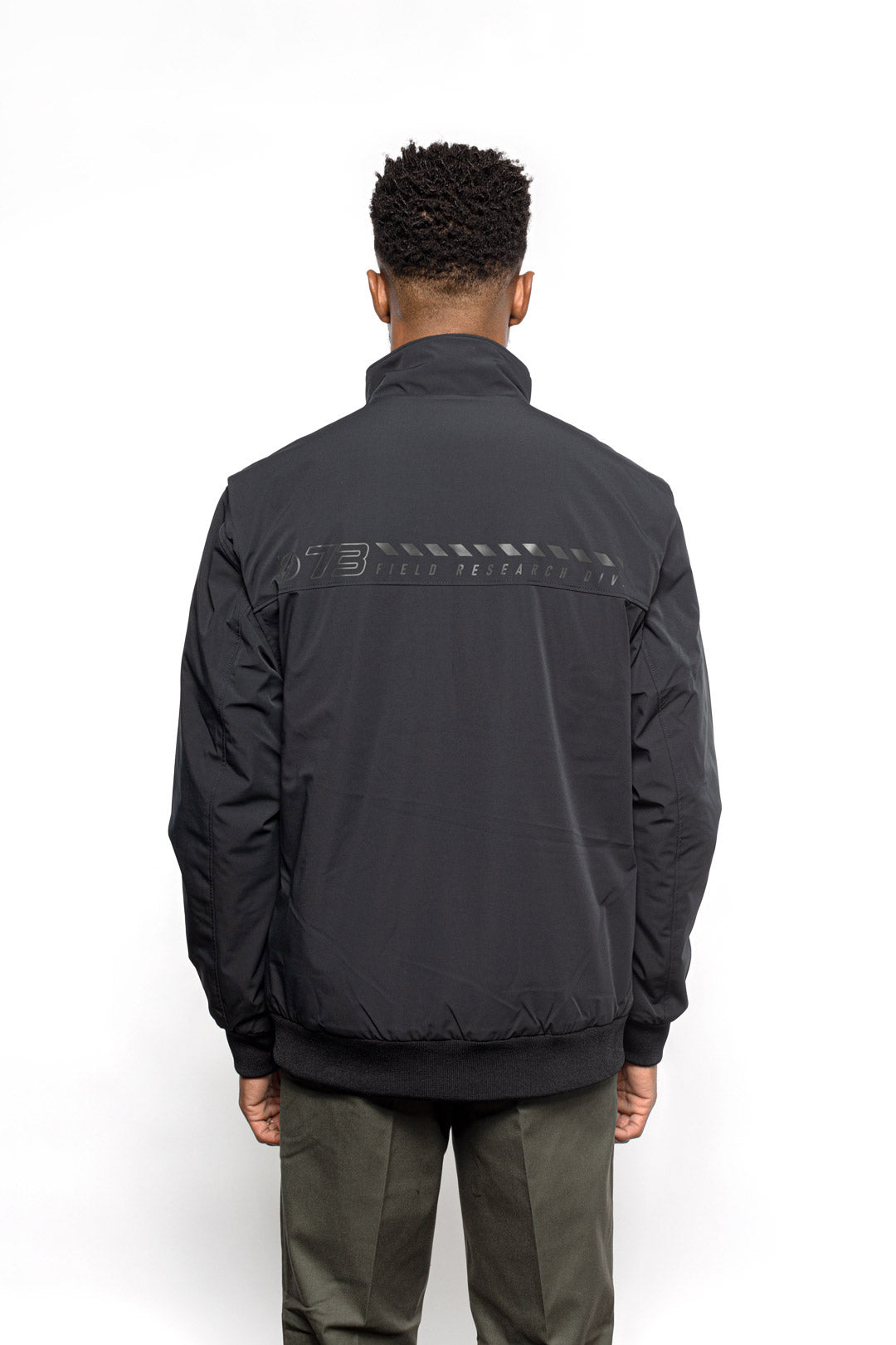 Back view of Male model wearing Royce Harrington Jacket in black colorway.