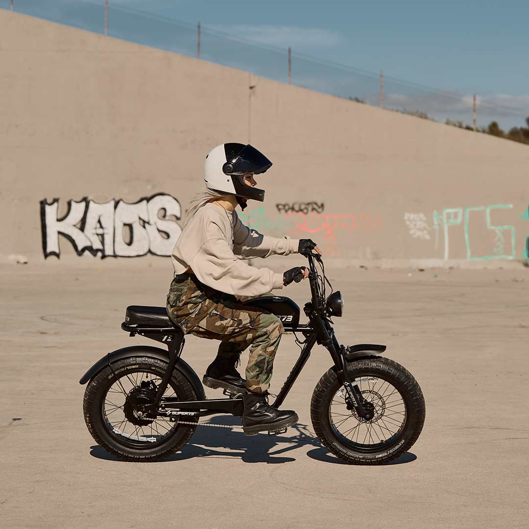 Young woman riding across frame on her SUPER73 S2 ebike with graffiti walls in the background