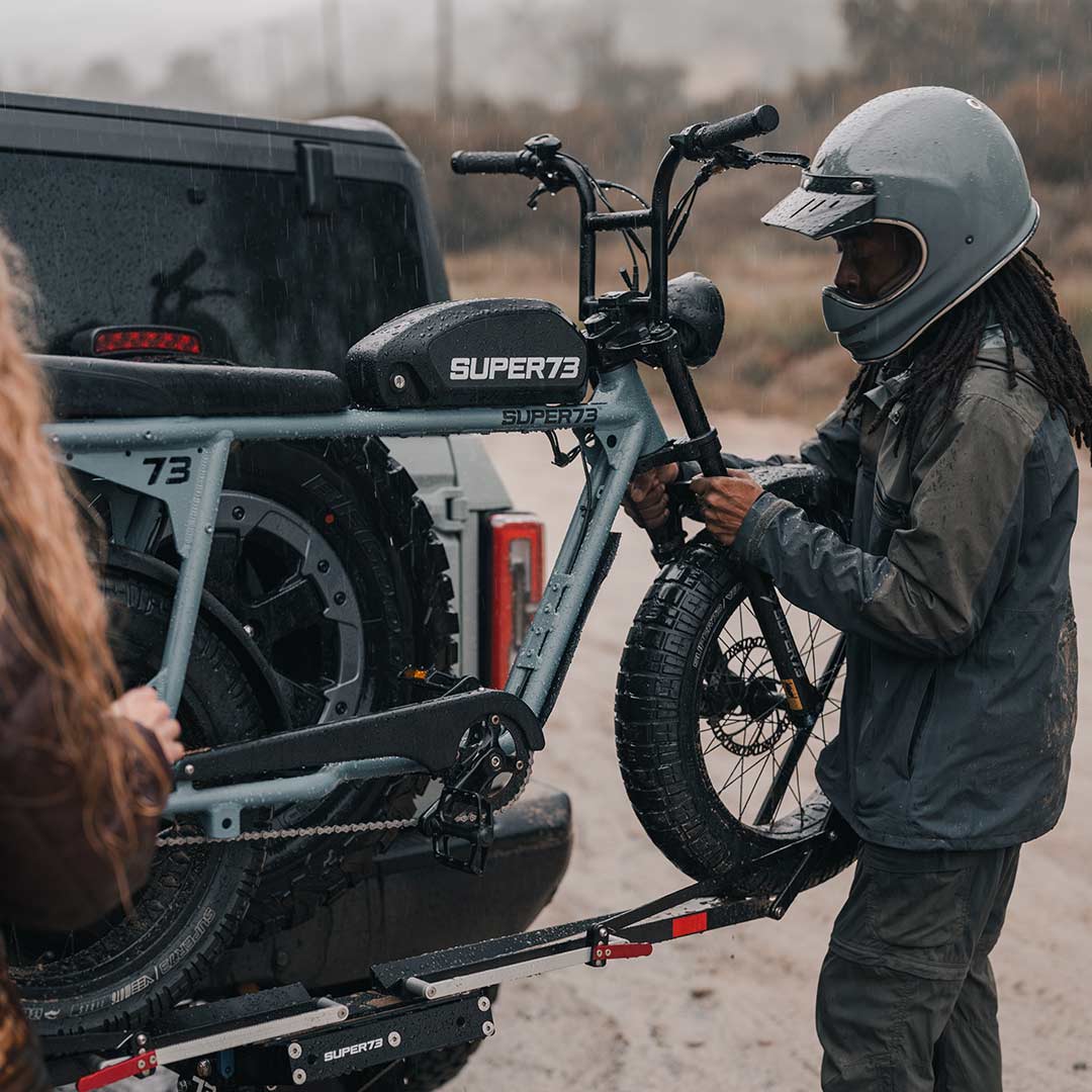 Two friends putting their SUPER73 S2 ebike on the 1Up rack on the back of their bronco on a rainy day