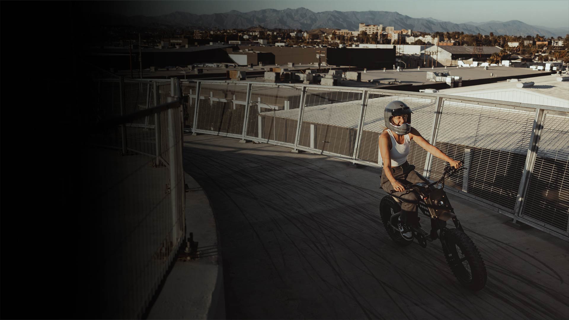 Young woman riding a Super73 ebike on a highway, wearing a helmet and laughing