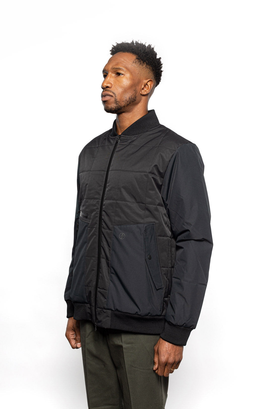 Side view of Male model wearing Sipes Varsity Jacket in black colorway.