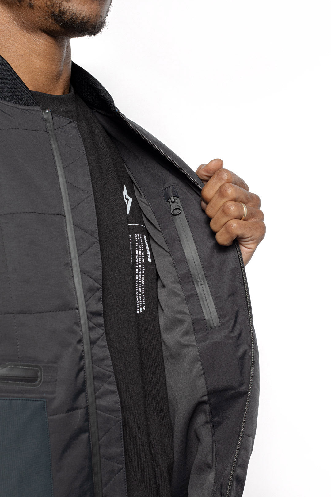 Male model showing inner details of Sipes Varsity Jacket in black colorway.
