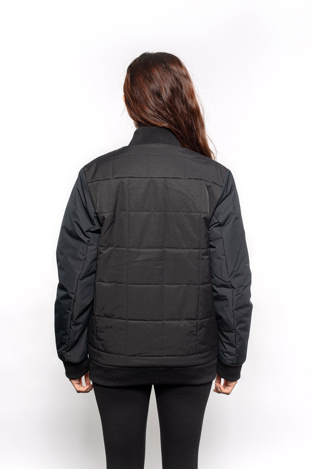 Back view of Female model wearing Sipes Varsity Jacket in black colorway.