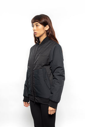 Side view of Female model wearing Sipes Varsity Jacket in black colorway.