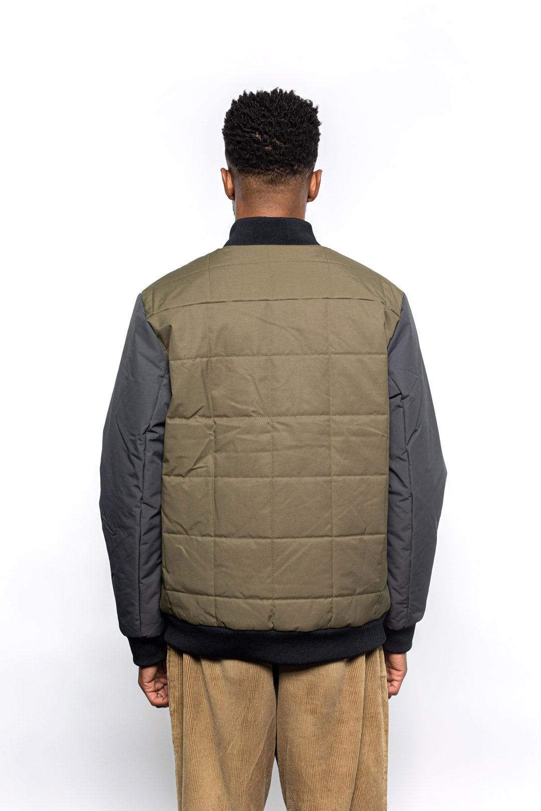 Back view of Male model wearing Sipes Varsity Jacket in dark fatigue colorway.