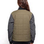 Back view of Female model wearing Sipes Varsity Jacket in dark fatigue colorway.