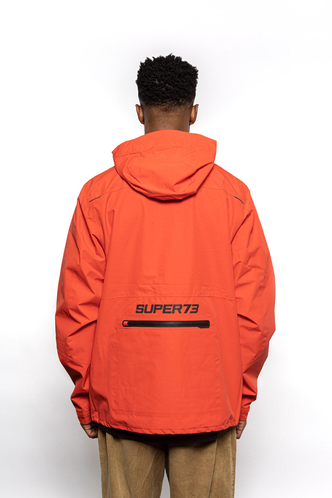 Back view of Male model wearing Vale Packable Anorak in blood orange colorway.